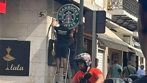 Momento en que los operarios colocan el logo que ser&aacute; sustituido por el del comercio / Cedida
