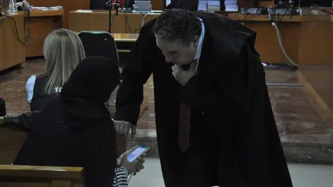  Uno de los abogados hablando con una acusada antes del inicio del juicio este martes. 