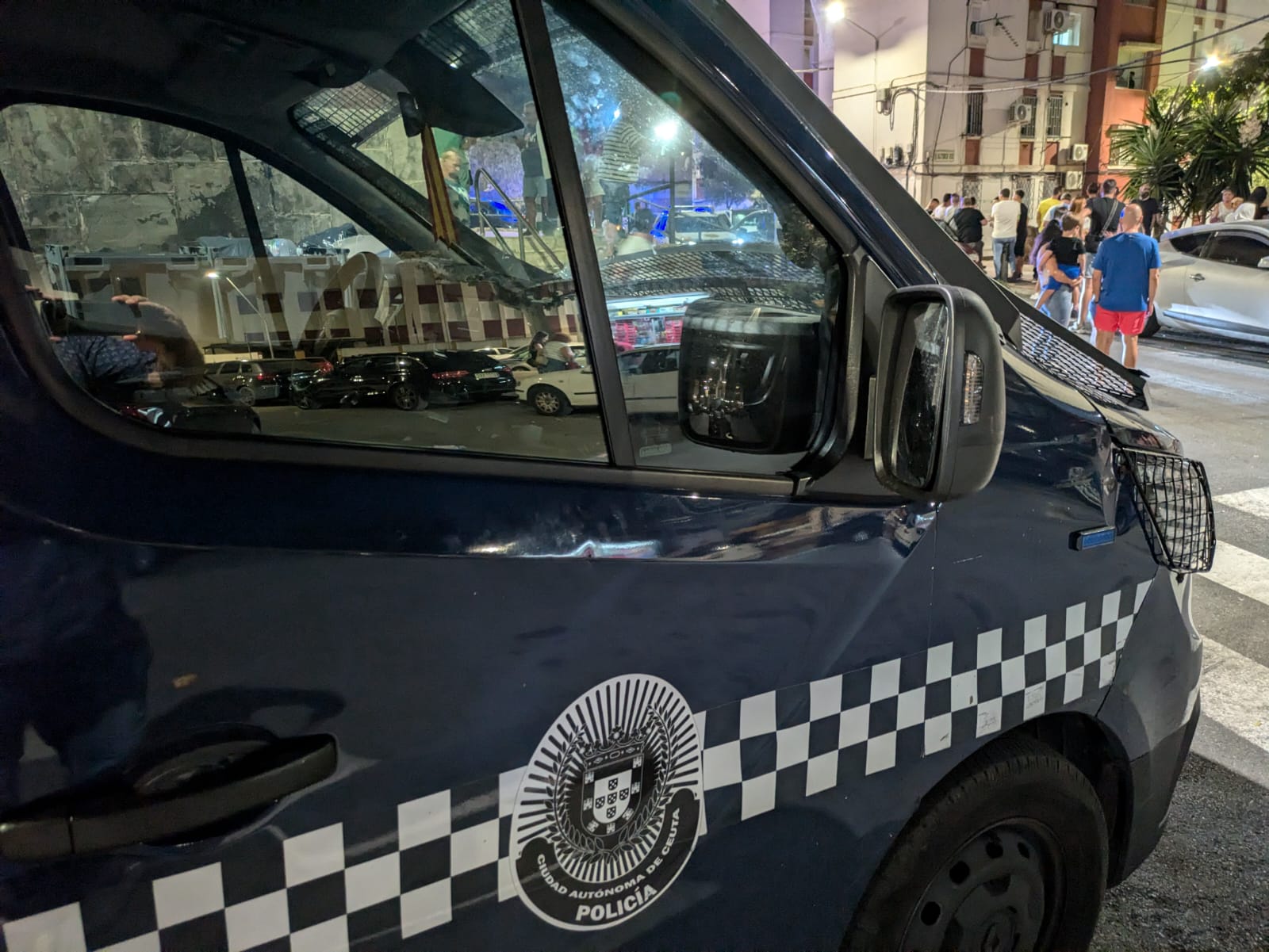 Varios vecinos, tras un vehículo policial / Rafa Báez